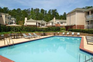 a large swimming pool with chairs and umbrellas at Sonesta ES Suites Atlanta Alpharetta Windward in Alpharetta