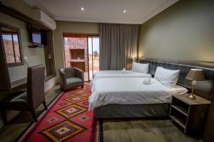 um quarto de hotel com uma cama e uma cadeira em Sangiro Game Lodge em Bloemfontein