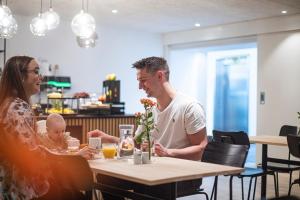 Hotel Djurhuus في تورشافن: رجل وامرأة يجلسون على طاولة مع طفل