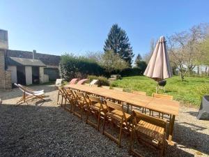 a group of wooden benches with an umbrella at La Villa Dorange, EXCEPTIONNELLE et SPACIEUSE in Sailly-Flibeaucourt