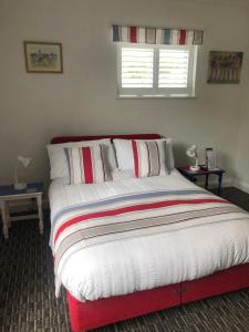 a bedroom with a bed with a red and white blanket at Tredara Bed & Breakfast in Truro