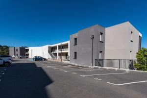a parking lot with a white building and a car at L'eclat de Stagnola in Pietrosella