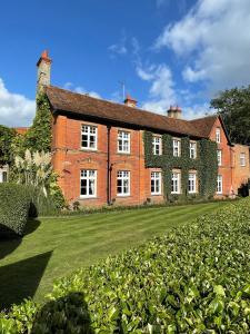 una gran casa de ladrillo rojo con un patio verde en Worlington Hall en Worlington