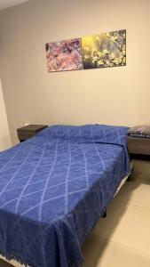 a bed with a blue comforter in a room at Departamento 1 dormitorio, Saenz Peña. in Santiago del Estero