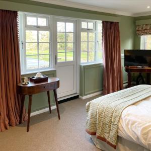 a bedroom with a bed and a desk and windows at Worlington Hall in Worlington