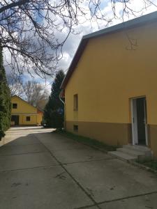 a yellow building with a door and a driveway at Podlovics Tanya Panzió in Kemecse