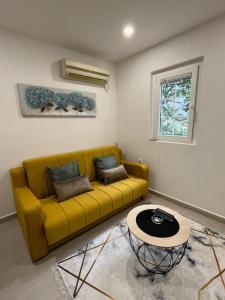 un sofá amarillo en una sala de estar con mesa en Dolce Casa en Kotor