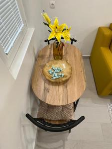 una mesa de madera con un jarrón con una flor amarilla. en Dolce Casa en Kotor
