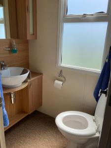 a bathroom with a toilet and a sink and a window at Caravan Skegness GB 148 in Chapel Saint Leonards