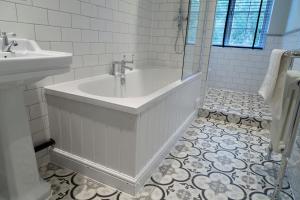 Baño blanco con bañera y lavamanos en Worlington Hall en Worlington