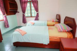 two twin beds in a room with a window at The Room Concept Homestay in Kuah