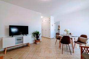 アルブフェイラにあるHoliday 1 Bed Apartment with pool in Albufeiraのリビングルーム(テレビ、テーブル、椅子付)