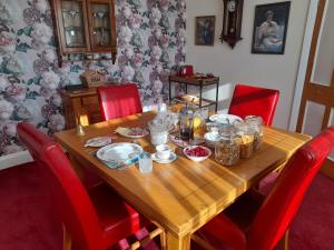 drewniany stół z czerwonymi krzesłami wokół niego z jedzeniem w obiekcie Bastwick House B&B w mieście Great Yarmouth