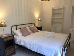 una camera da letto con letto, lenzuola e cuscini bianchi di Maison de campagne Chez Georges a Saint-Sulpice-de-Pommiers
