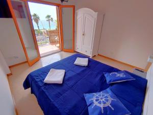 een slaapkamer met een blauw bed met 2 handdoeken erop bij Taormina by the sea in Mazzeo
