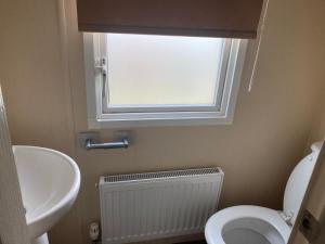 a bathroom with a sink and a toilet and a window at Skegness B10 in Chapel Saint Leonards