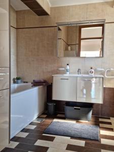 een badkamer met een wastafel, een bad en een spiegel bij ZARA BEAUTY in Kožino