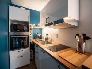 une cuisine avec des placards blancs et un comptoir en bois dans l'établissement HESPERIE Thermes, à Chamalières