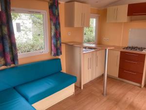 a small kitchen with a blue couch in a room at Camping l’r pur in Saint-Vincent-sur-Jard