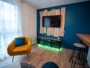 un salon avec une chaise et une télévision sur un mur bleu dans l'établissement HESPERIE Thermes, à Chamalières