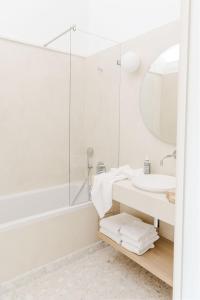 bagno bianco con lavandino e specchio di Hôtel Restaurant Les Arnelles a Saintes-Maries-de-la-Mer