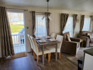 a dining room with a table and chairs and a couch at 2BR-Sleeps6-Fireplace-Parking-Patio-Seaside in Clacton-on-Sea
