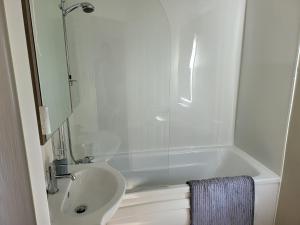 a white bathroom with a tub and a sink at 2BR-Sleeps6-Fireplace-Parking-Patio-Seaside in Clacton-on-Sea