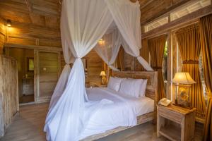 a bedroom with a white bed with a canopy at Wana Shanti Villa in Bringkit
