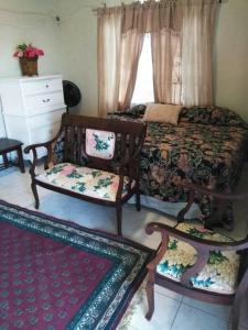 a bedroom with a bed and two chairs and a dresser at Remarkable 2-Bed Villa in Fair Prospect Sea View in Port Antonio