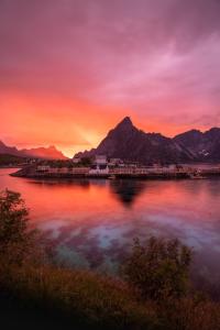 een zonsondergang boven een waterlichaam met bergen bij Sakrisøy Rorbuer in Reine