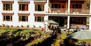 - un bâtiment blanc avec une cour dotée de chaises et de parasols dans l'établissement Ladakh Eco House, à Leh