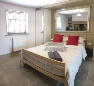 a bedroom with a large bed with red pillows and a mirror at 1700s Canalside Cottage Sleeps up to 12 Guests in Burnley