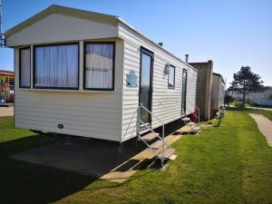 a white trailer with a ladder parked in the grass at Lovely 2-Bed caravan in Walton on the Naze in Walton-on-the-Naze