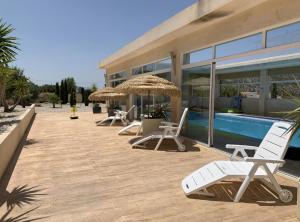 a row of chairs and umbrellas next to a pool at Stunning 3 bedroom villa near Pinoso 
