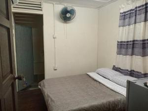 a small bedroom with a bed and a fan at Juara Cottage in Tioman Island