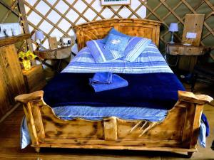 a wooden bed with blue sheets and blue pillows at Cosy and Inviting Waterside Luxury Yurt in Bembridge