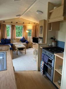 a kitchen and living room with a stove top oven at Cosy Quiet Static Caravan Mawgan Porth St Eval in Wadebridge