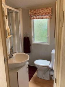 a bathroom with a sink and a toilet and a window at Cosy Quiet Static Caravan Mawgan Porth St Eval in Wadebridge