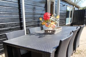 een tafel met stoelen en een vaas met bloemen erop bij Oud-Hollands Huus - Vakantiehuisje Veluwe in Ede