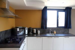 a kitchen with white cabinets and a microwave and a sink at Oud-Hollands Huus - Vakantiehuisje Veluwe in Ede +5 photos