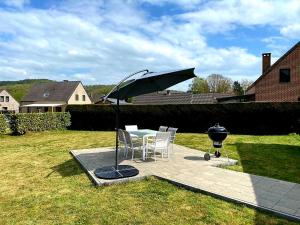 a patio with a table and an umbrella and a grill at Gîte au 14 - au calme avec jardin , proche de Dinant in Anhée