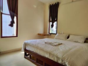 a bedroom with a large bed with two windows at Tatsat Hostel in Rishīkesh