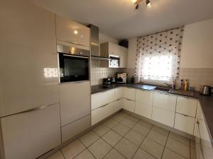a large kitchen with white cabinets and a window at Ferienhaus Vongerichten in Oberhausen