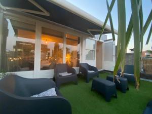 a patio with couches and chairs on the grass at The Jungle - duo studio with kingsize terrace in Groningen