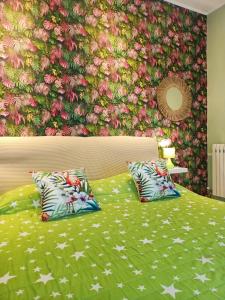 a green bed with two pillows and a floral wall at The 727 Sottomarina in Sottomarina
