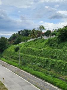 a grassy hill with a fence and a road at Kate's Corner @ One oasis Condo in Cagayan de Oro