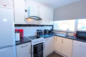 eine Küche mit weißen Schränken und einer schwarzen Arbeitsplatte in der Unterkunft Pet friendly sleeps 6 Chalet Bridlington free elec in Bridlington