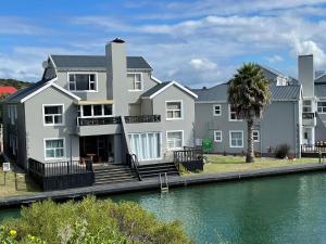 a large house next to a body of water at Jamaican Palms 27, Marina Martinique in Jeffreys Bay