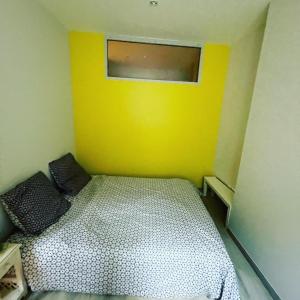 a small room with a bed with a yellow wall at T2 hypercentre Libourne 5 min St Emillon in Libourne
