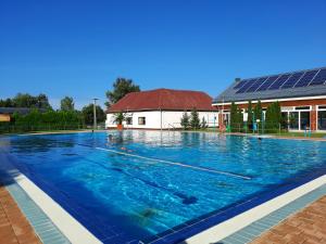 a swimming pool with blue water in front of a building at Csengő Vendégház in Kiskőrös